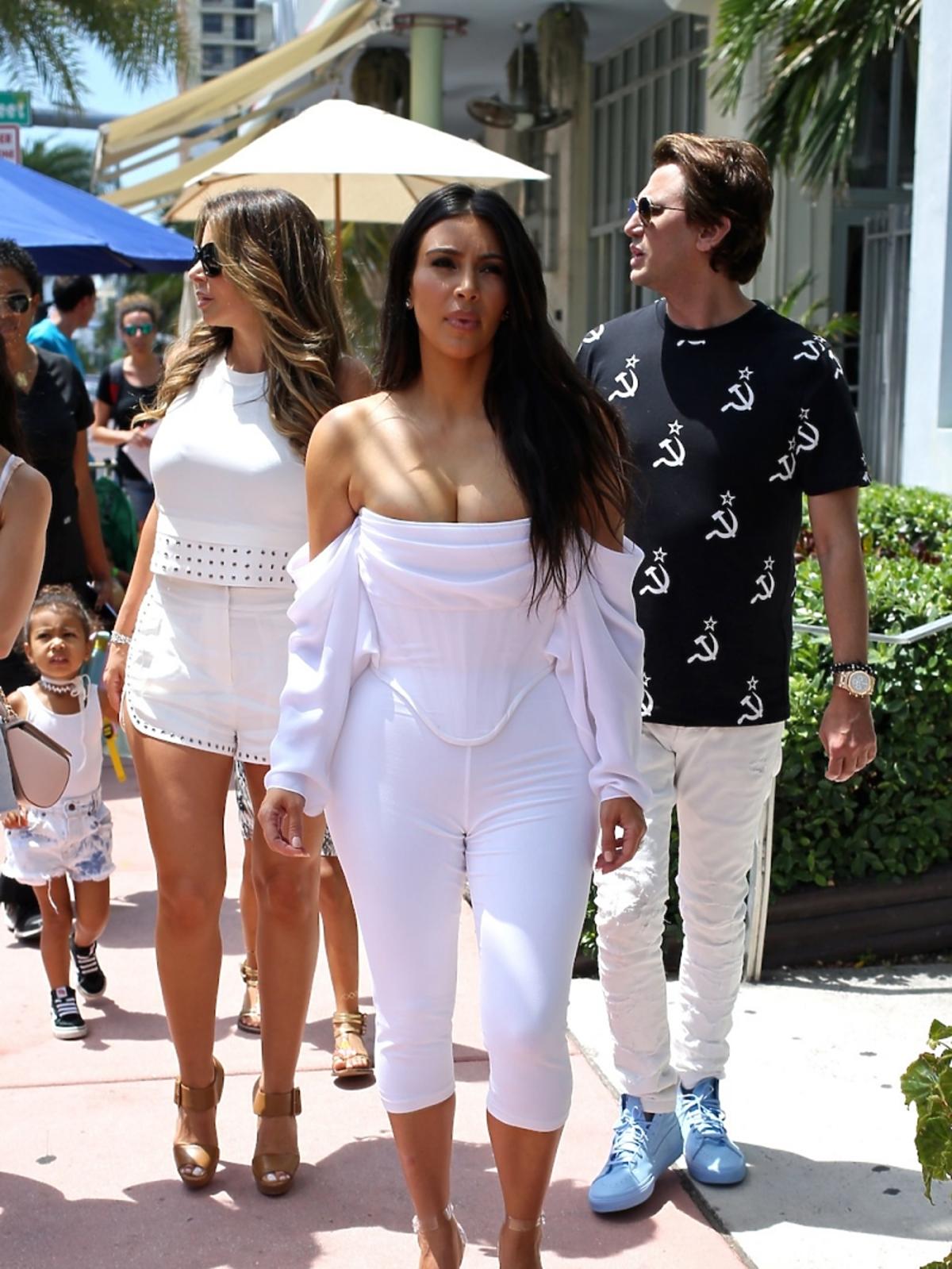 Biała stylizacja Kim Kardashian z za małą bluzką, ledwie mieszczącą obfity biust