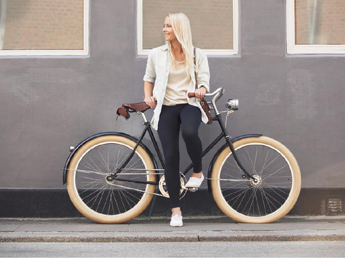 Wysportowana blondynka w modnej stylizacji pozuje na rowerze