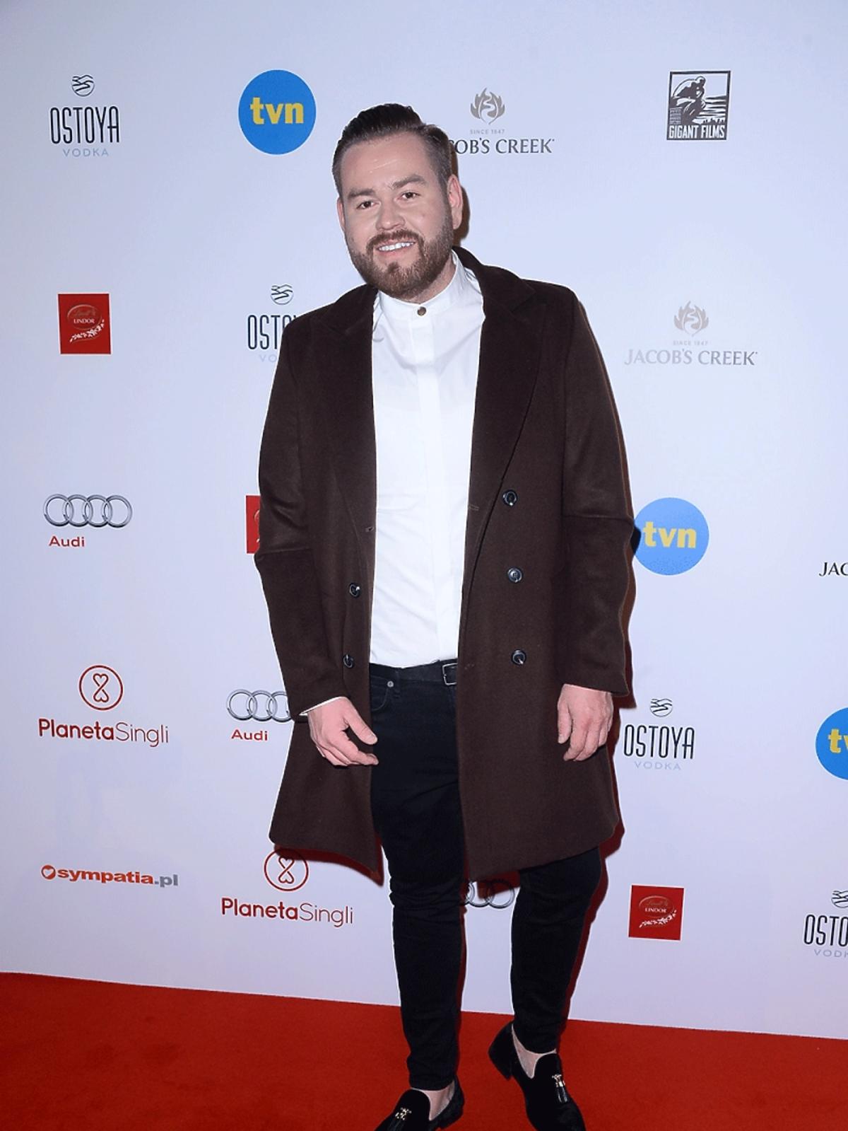 Tomasz Olejniczak w białej koszuli i brązowym płaszczu