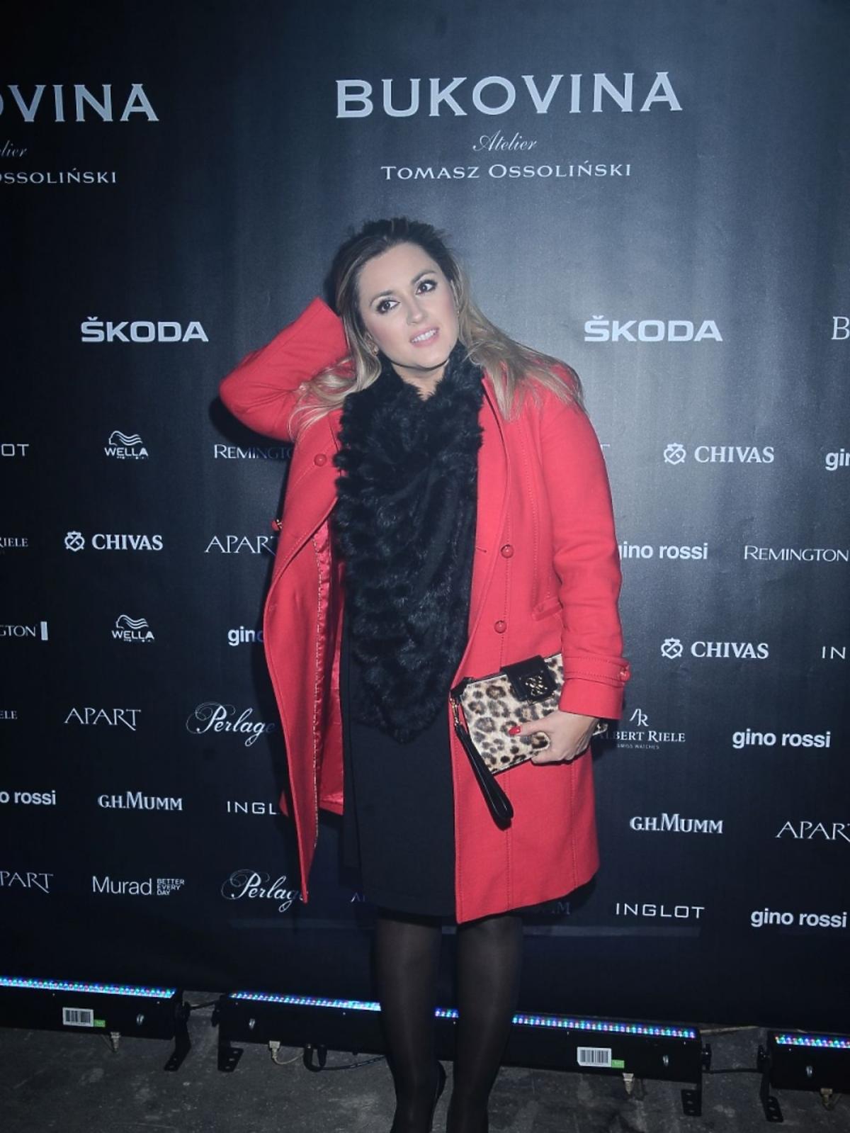 Karolina Szostak w czarnej sukience i z torebką w panterkę na pokazie Tomasza Ossolińskiego