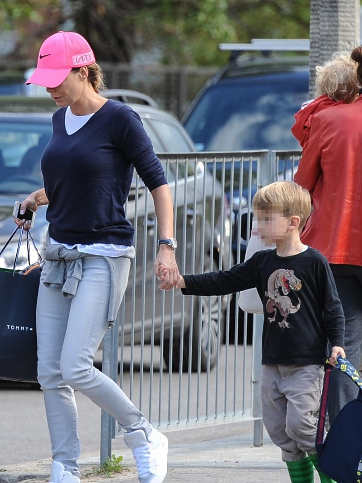 Małgorzata Rozenek w rózowej czapce, granatowym swetrze i białych butach z synem na ulicy