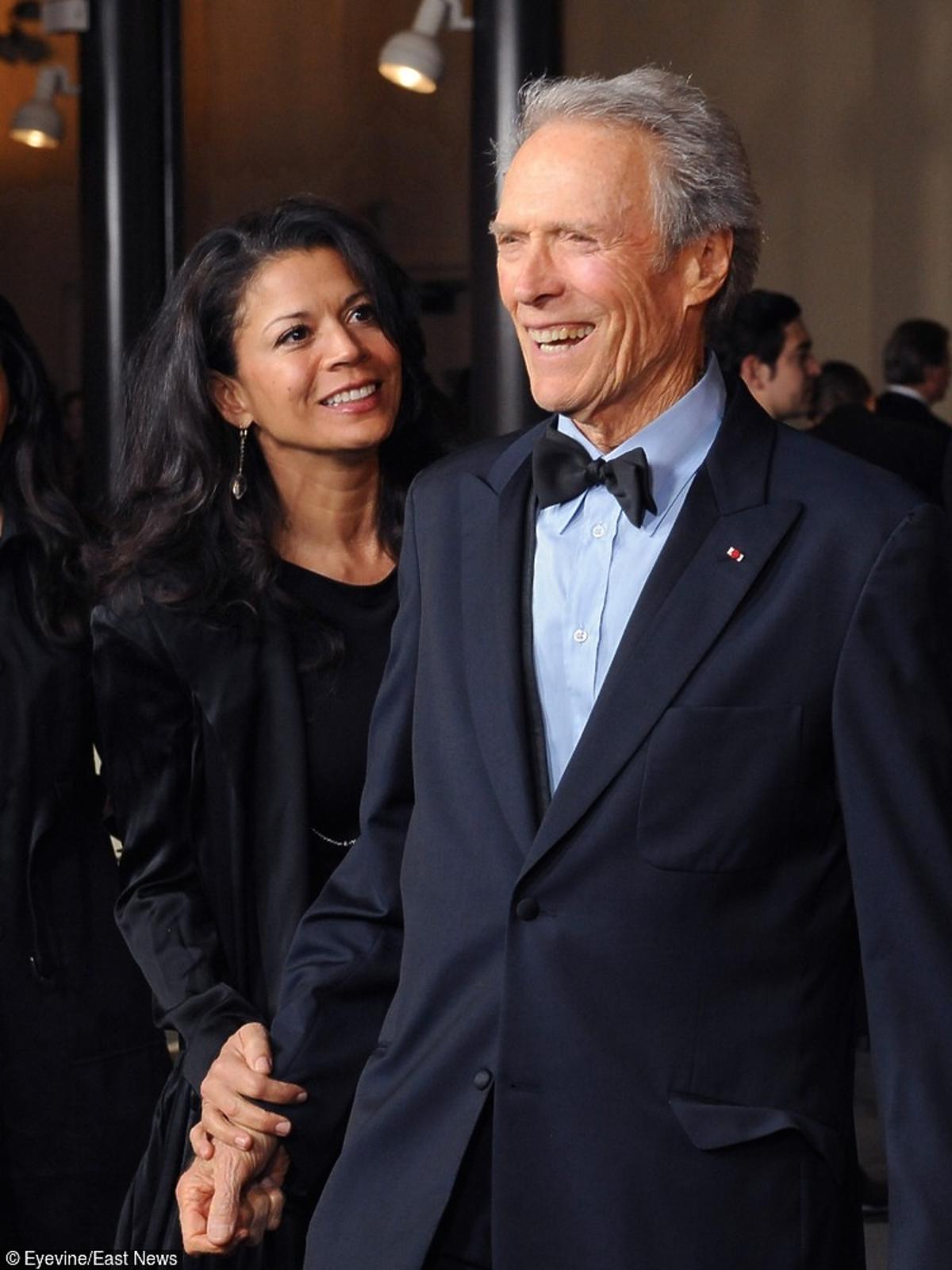 Clint Eastwood granatowym garniturze w muszką stoi z żoną Diną Ruiz która jest w czarnej sukience