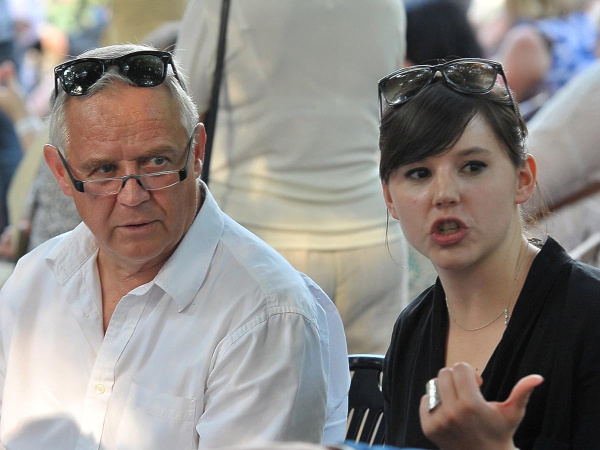 Marek Kondrat w białej koszuli siedzi ze zdziwioną Antoniną Turnau, która ma na sobie czarną bluzkę, obije mają na głowie okulary