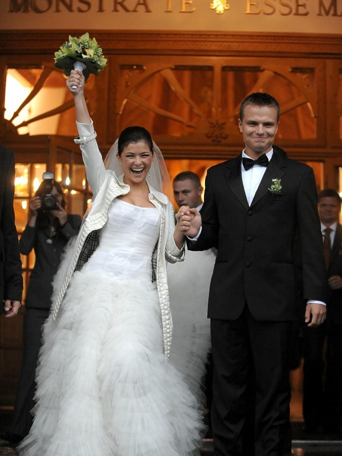 Katarzyna Cichopek w białej sukni ślubnej z bukietem kwiatów. Marcin Hakiel w czarnym, ciemnym garniturze z muchą