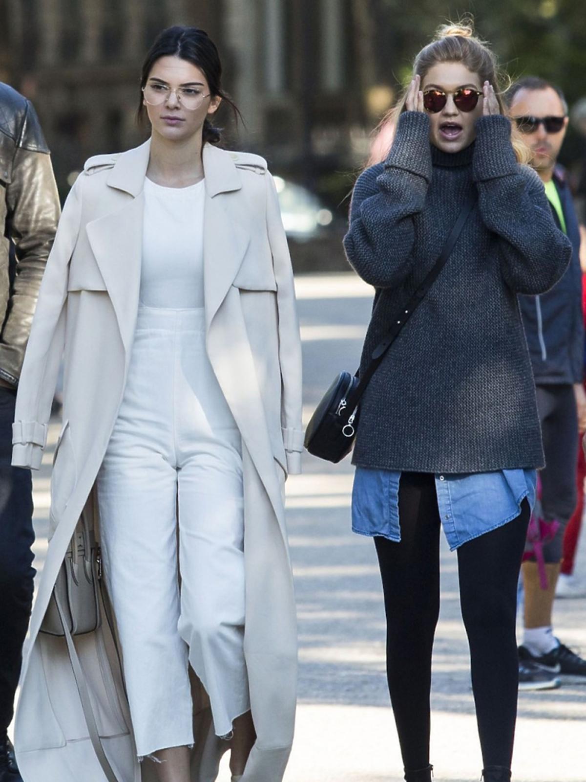 Kendall Jenner w beżowych płaszczu, białych spodniach i topie, beżowych butach z gwiazdkami, okularach