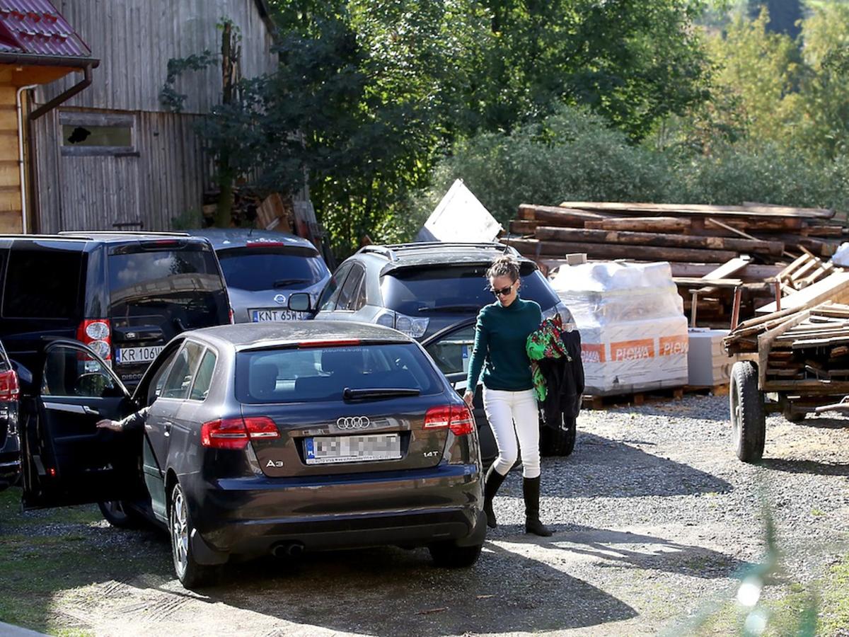 Alicja Bachleda-Curuś w białych spodniach i czarnych kozakach na parkingu