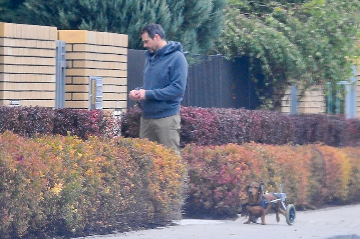 Paweł Deląg w dresie na spacerze w psem, który porusza się na wózku inwalidzkim