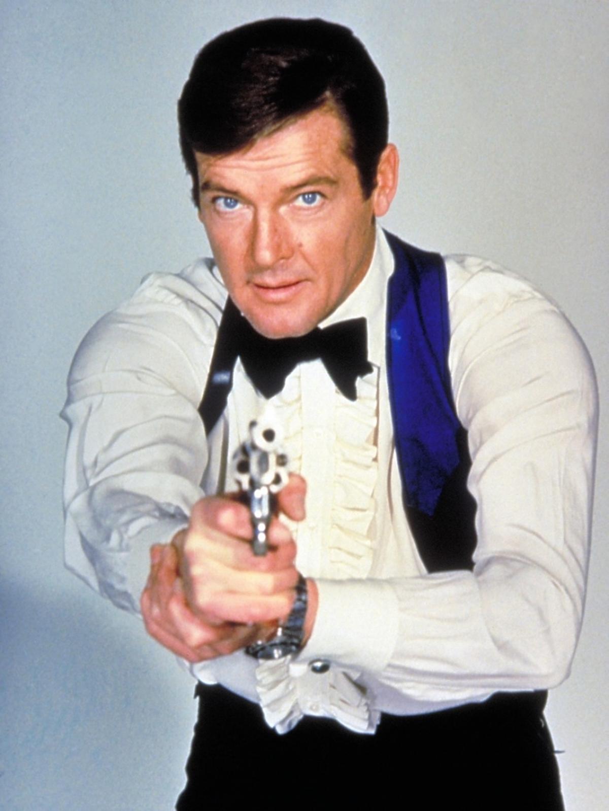  Roger Moore w białej koszuli i czarnej muszce celuje z pistoletu w obiektyw