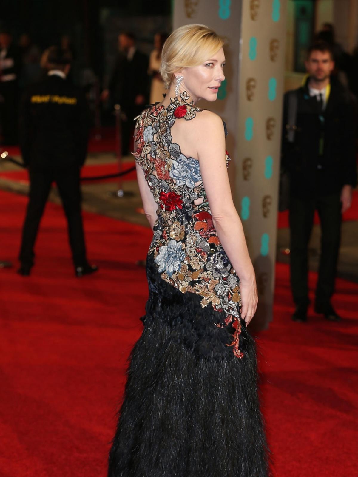 Cate Blanchett w sukni bogato zdobionej na górze i z czarnych piór na dole na czerwonym dywanie