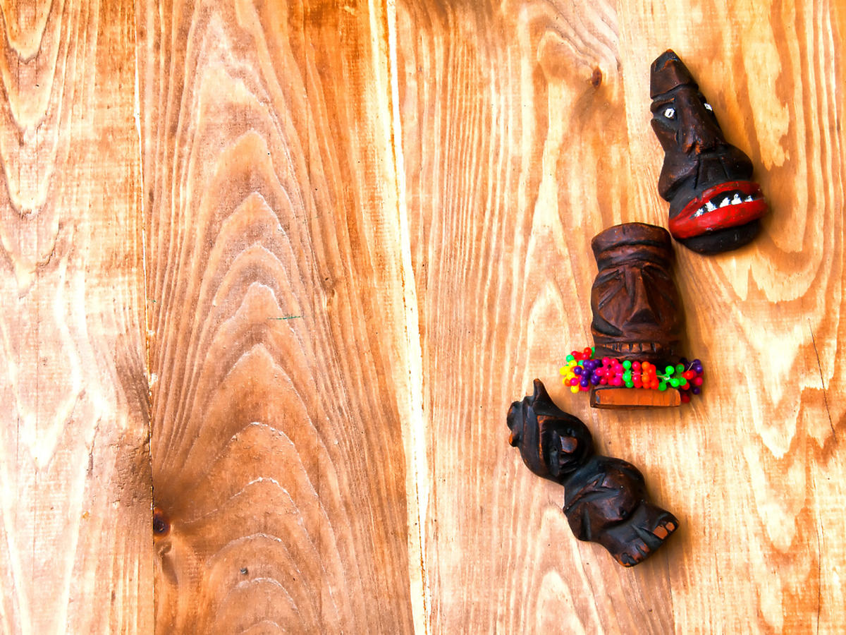 3 figurki afrykańskie z drewna leżą na ziemi.
