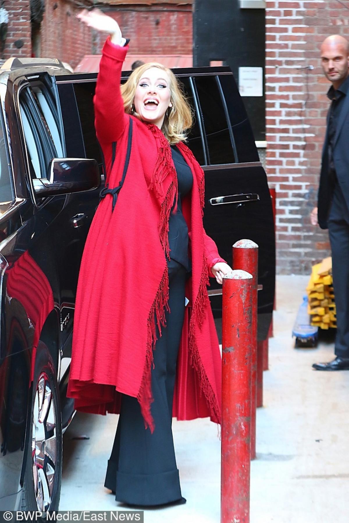 Adele w czerwonym płaszczu macha ręką