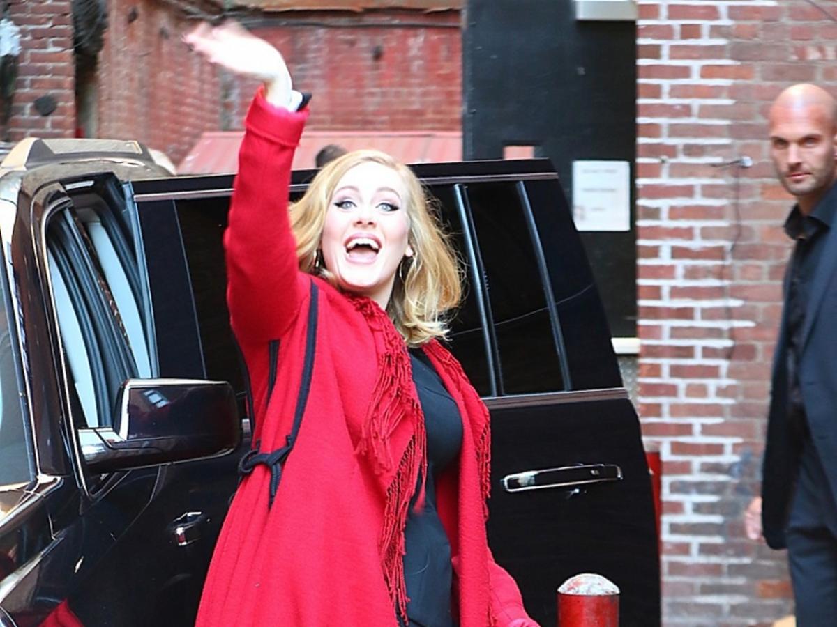 Adele w czerwonym płaszczu macha ręką