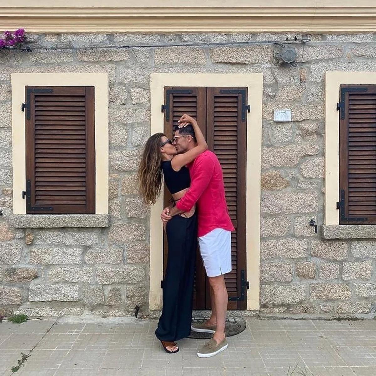 Anna Lewandowska i Robert Lewandowski przytulają się i całują na tle kamiennego domu