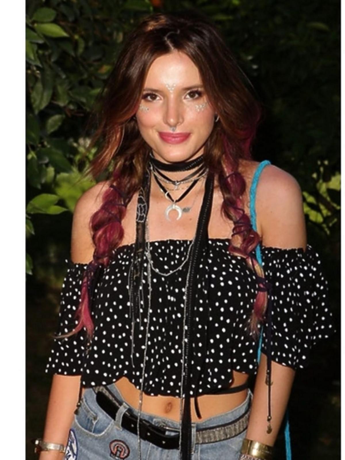 Bella Thorne w bluzce bez ramion i ze srebrnymi naklejkami na twarzy