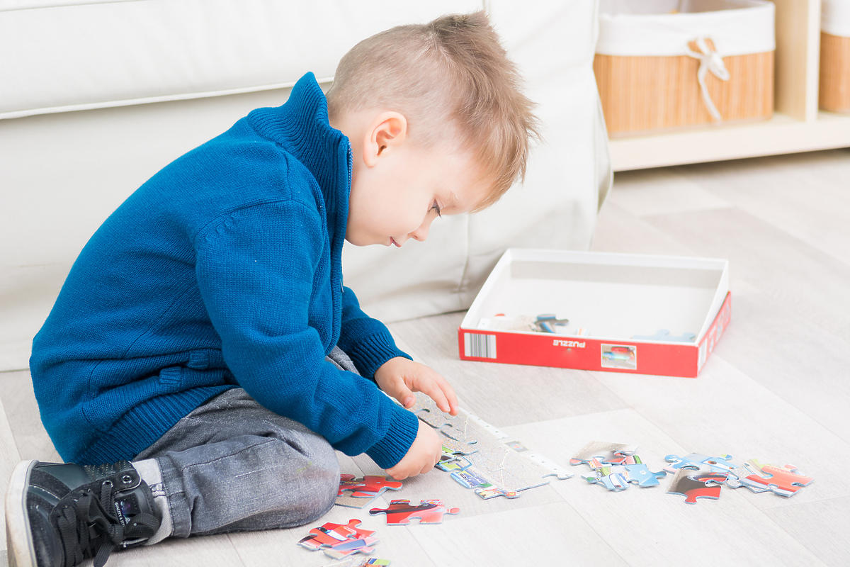 Dziecko układa puzzle na dywanie