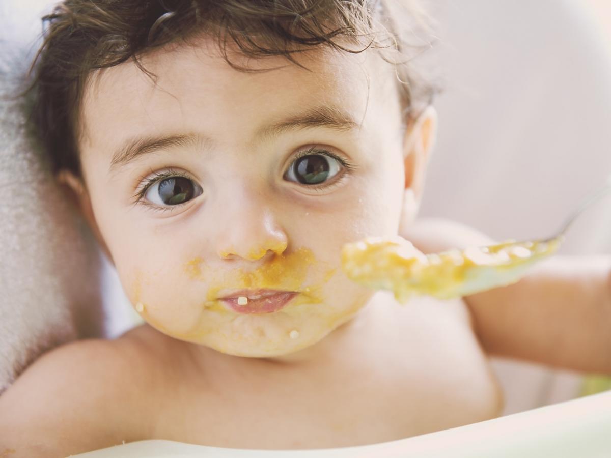 Dziecko z brudną buzią w trakcie jedzenia. 