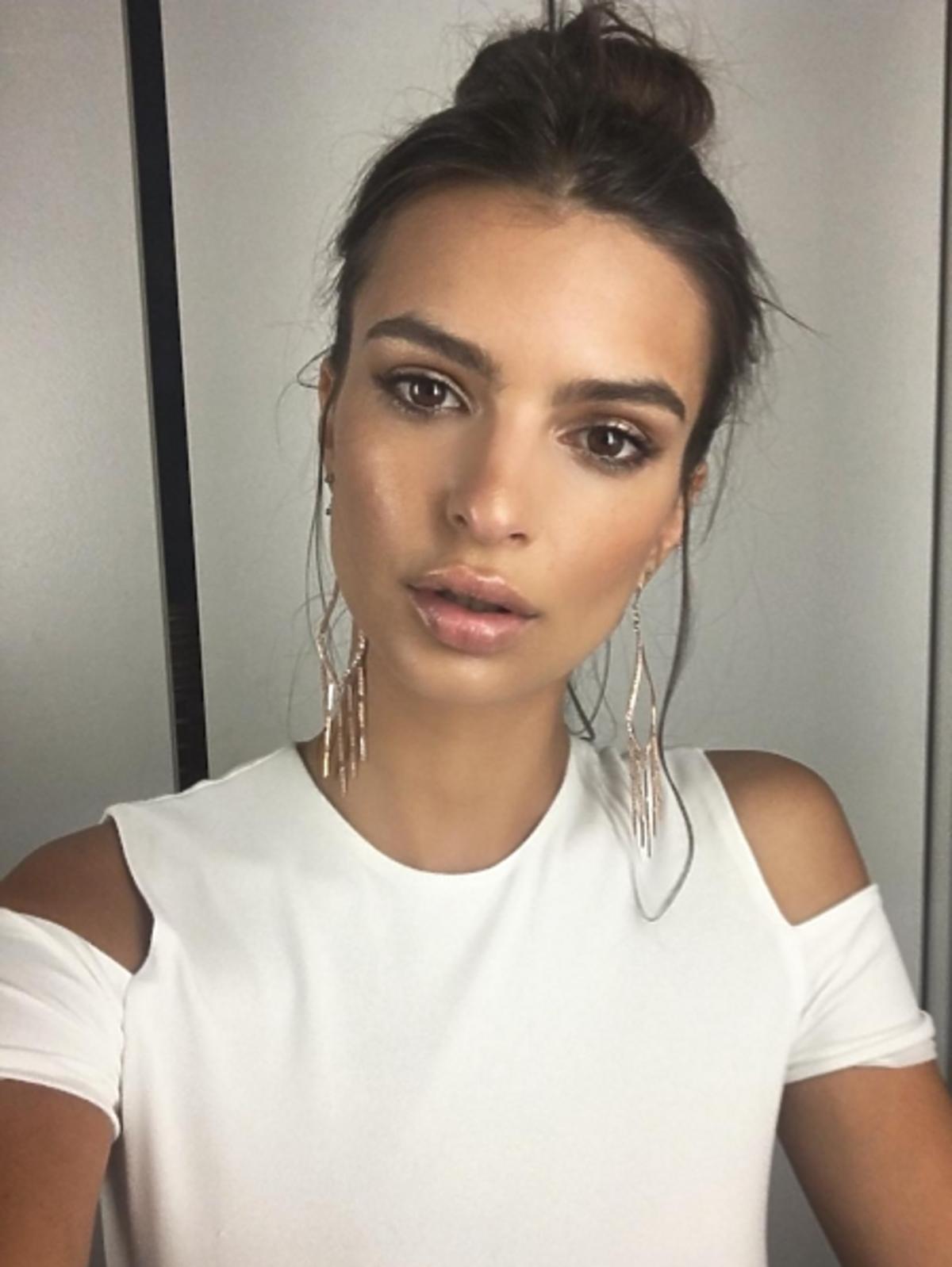 Emily Ratajkowski w białej bluzce, koku i złotych kolczykach