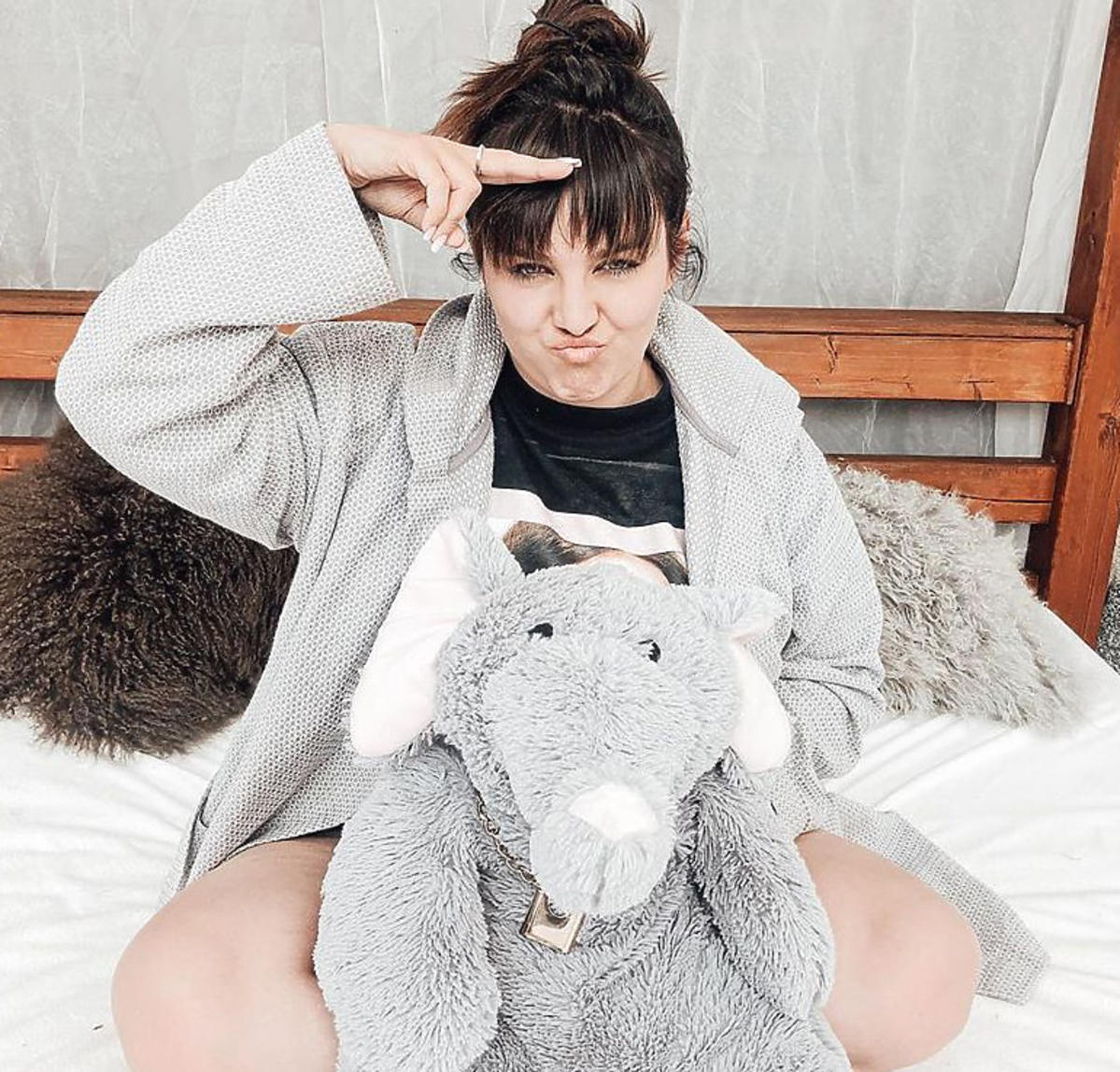 Ewa Farna na łóżku w szarej bluzie