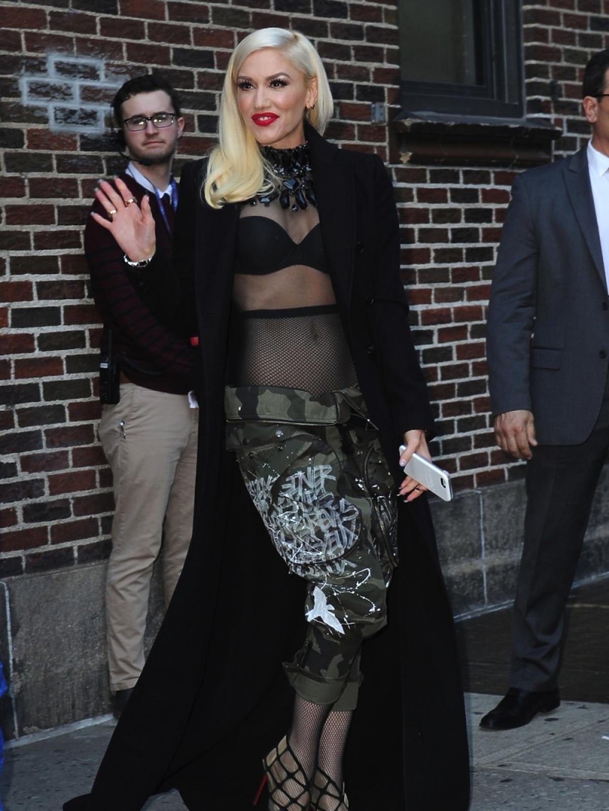 Gwen Stefani w czarnym płaszczu, widocznym biustonoszu i spodniach moro