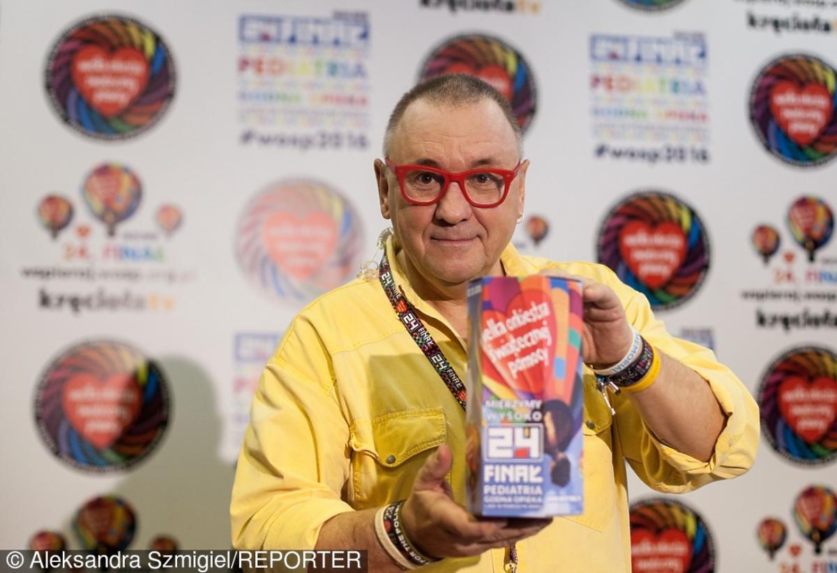 Jerzy Owsiak w żóltej koszuli trzyma puszkę WOŚP