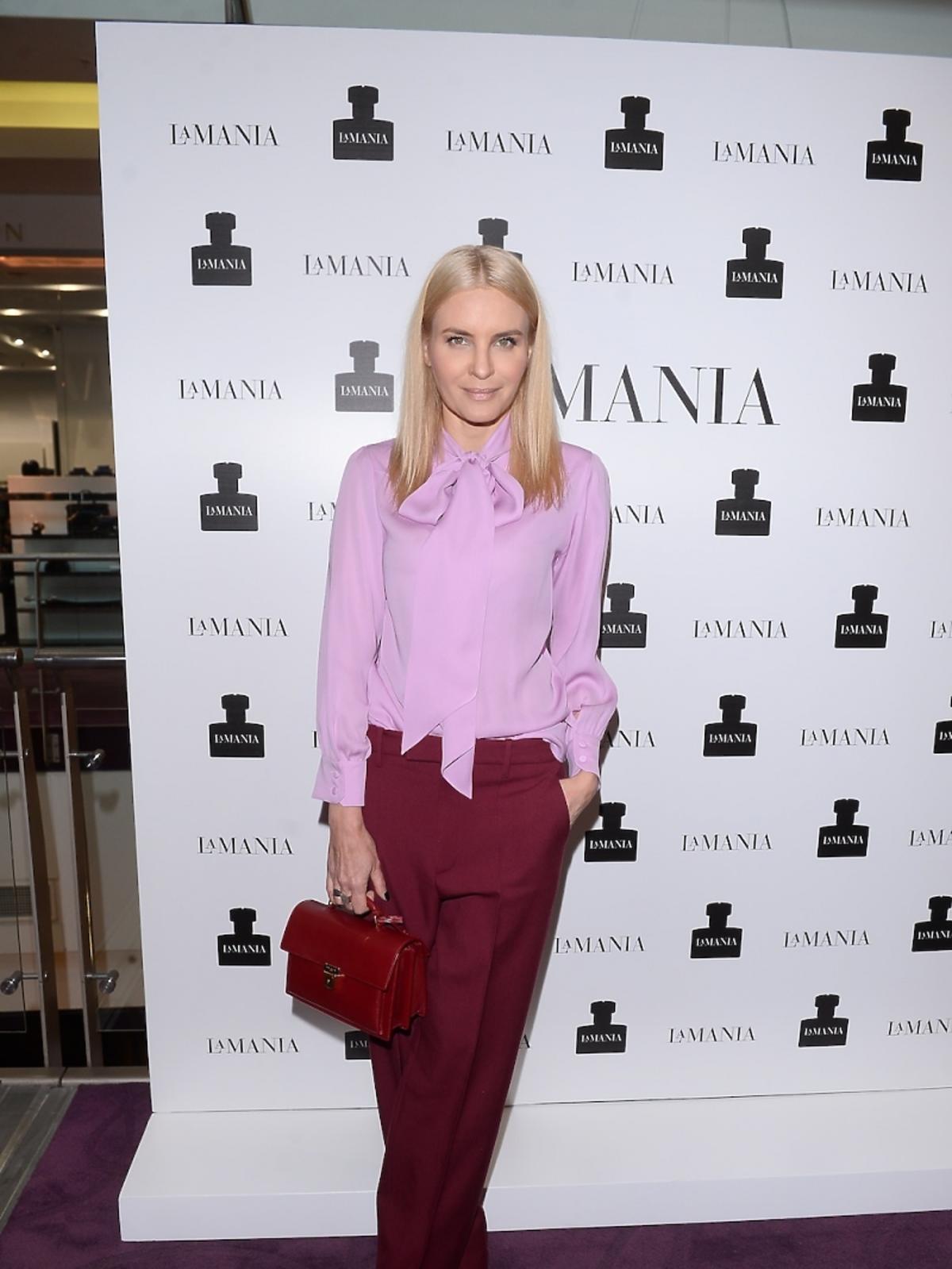 Joanna Horodyńska w blond włosach, różowej koszuli Gucci, w bordowych spodniach Gucci i z bordową torebką Saint Laurent