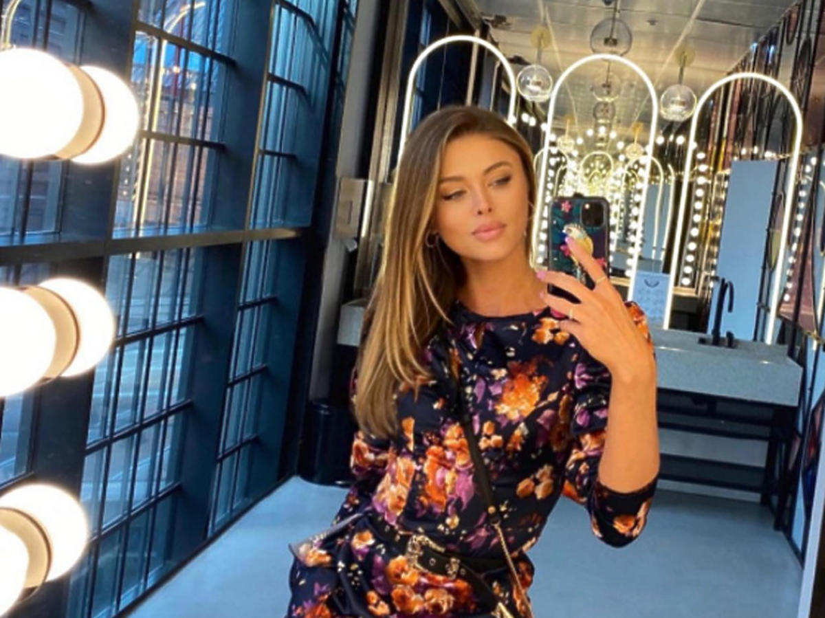 Joanna Opozda robi sobie selfie w lustrze, ma na sobie obcisłą, kwiatową sukienkę