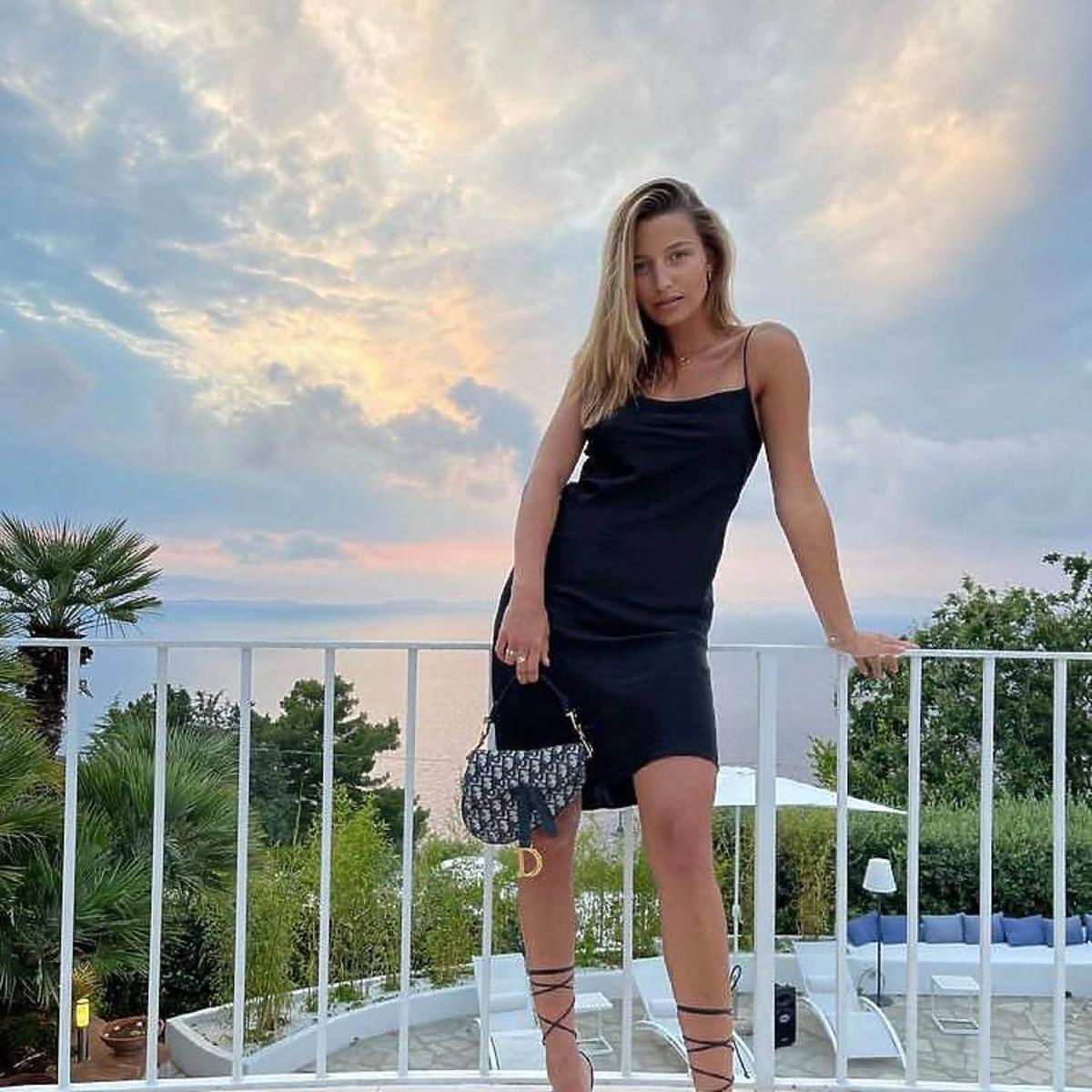 Julia Wieniawa w czarnej sukience i wiązanych sandałkach.