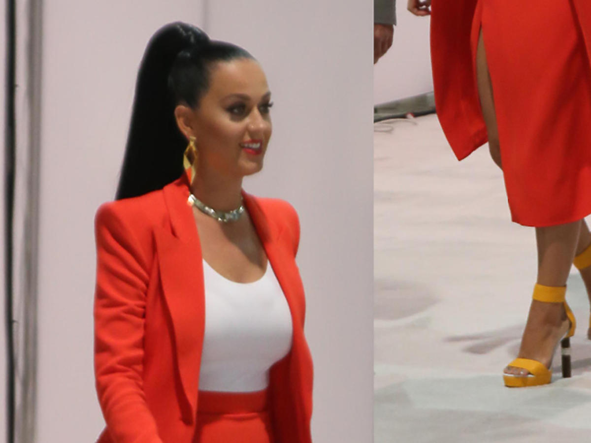 Katy Perry w czerwonym płaszczu, białym topie i butach wysokich