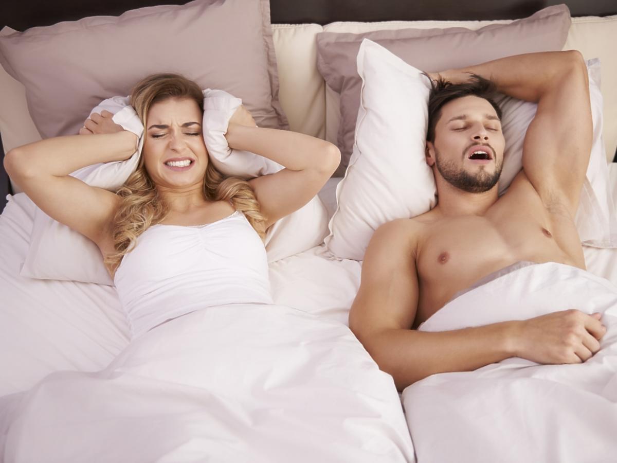 kobieta leży w łóżku z chrapiącym mężczyzną