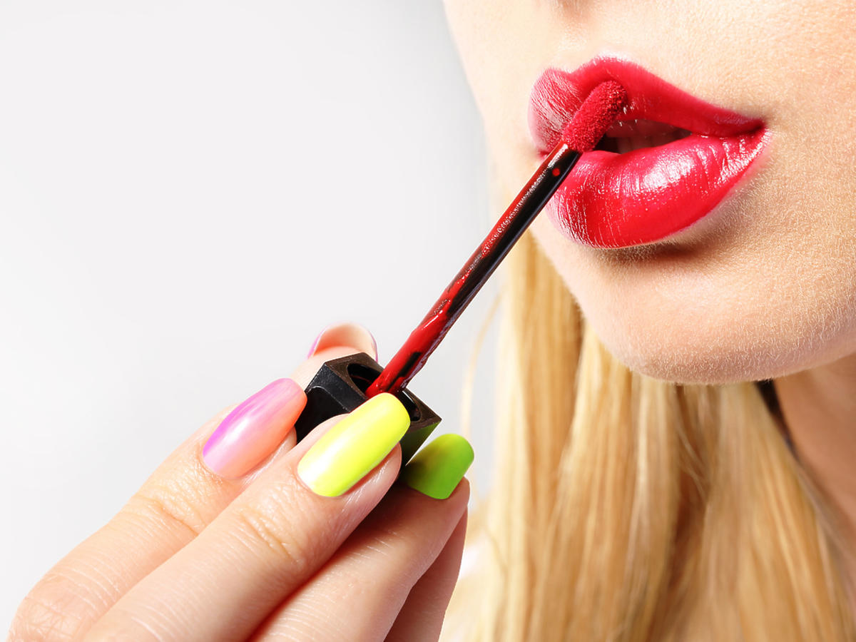 kobieta maluje czerwoną szminką usta