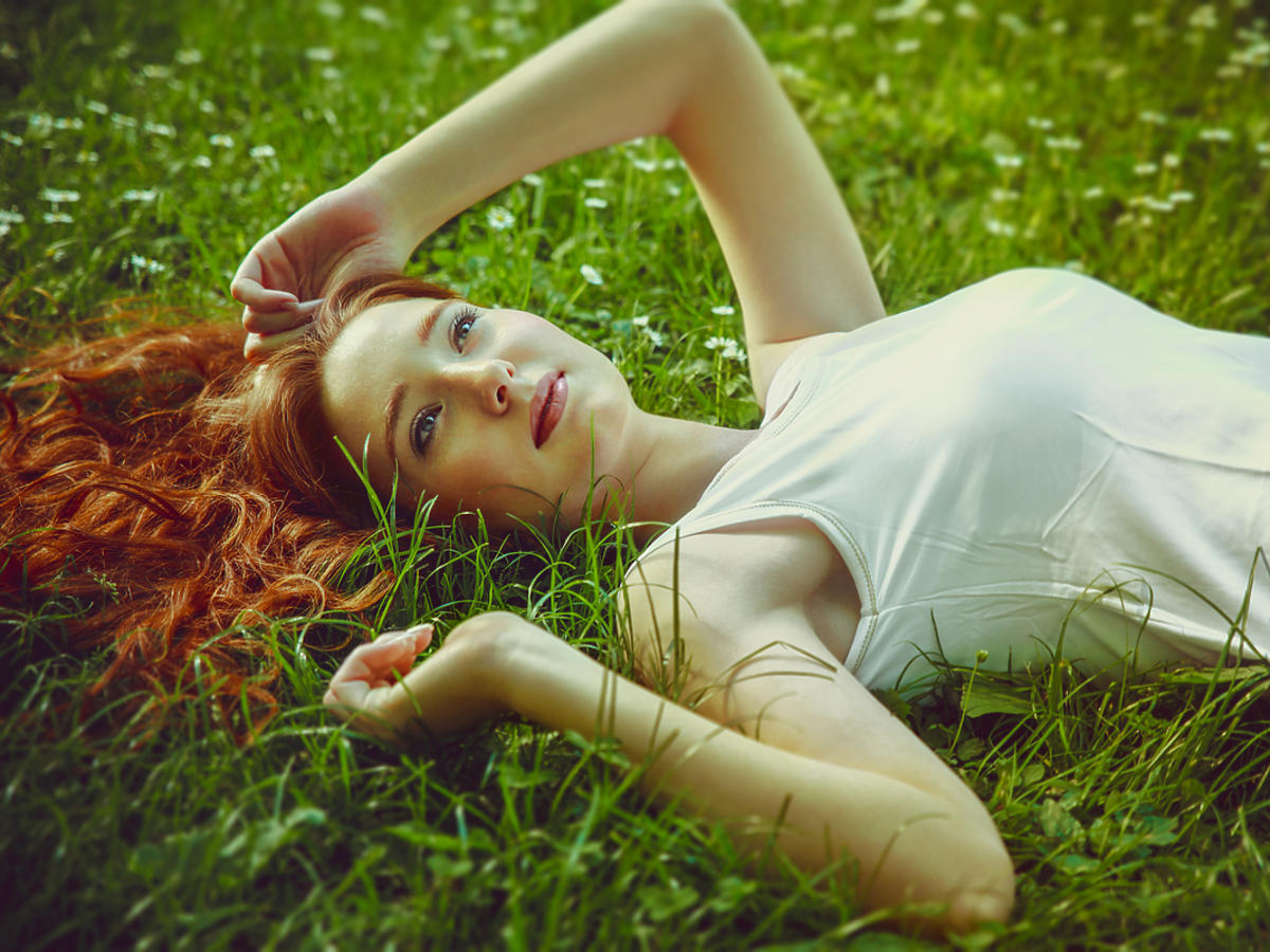 Kobieta o rudych włosach leży na trawie