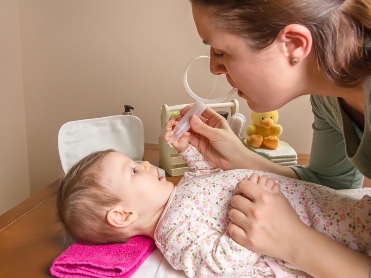 Kobieta podaje lekarstwo niemowlęciu