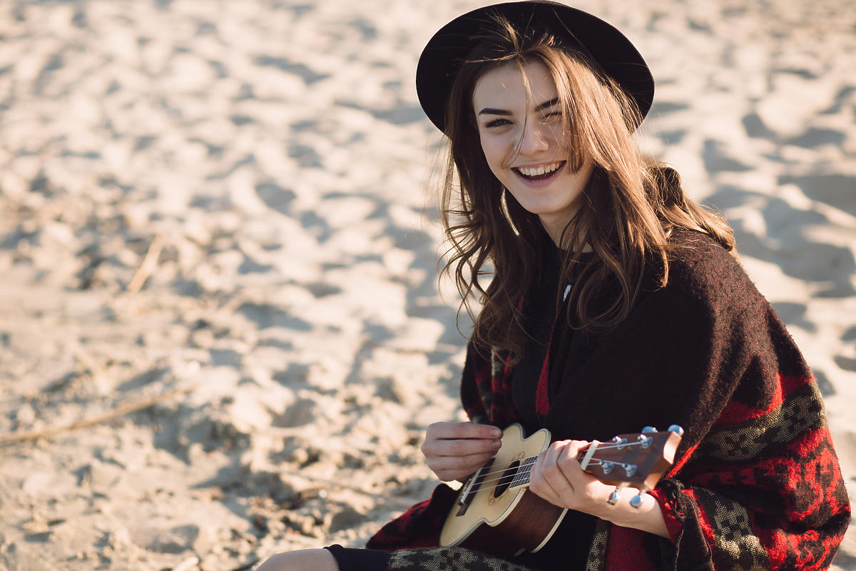 kobieta siedząca z ukulele na plaży