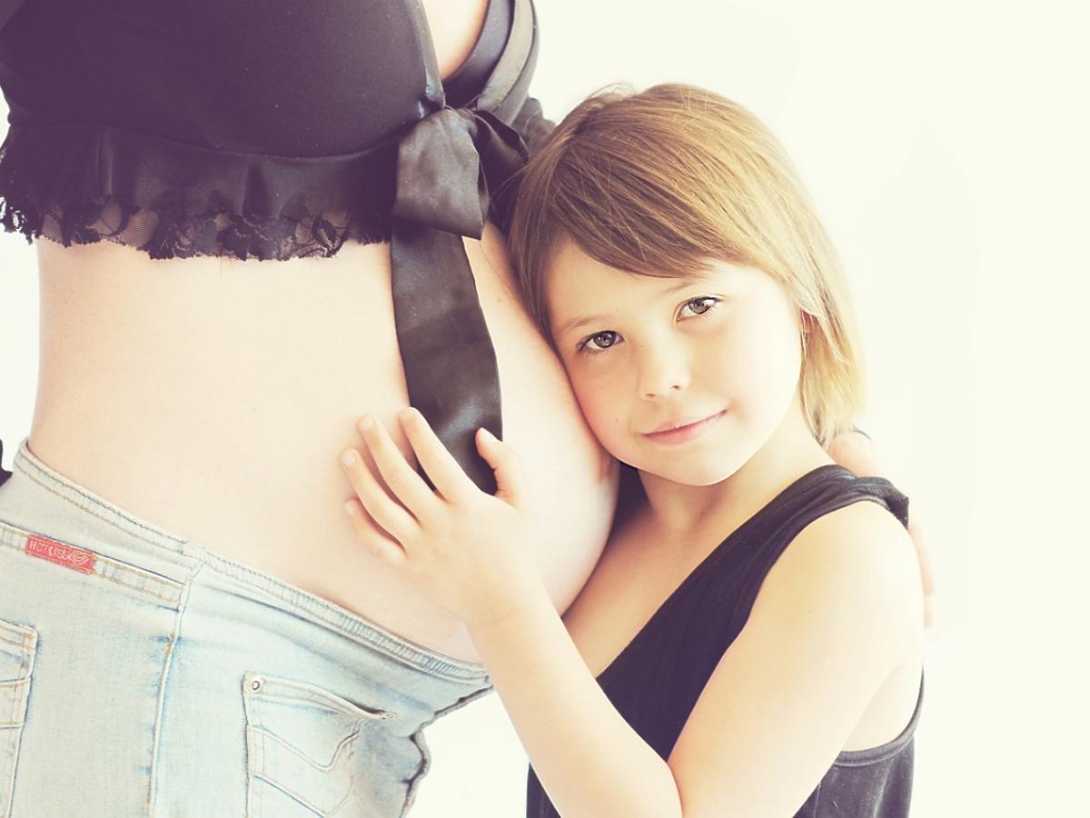 Kobieta w ciąży, obok niej stoi dziewczynka