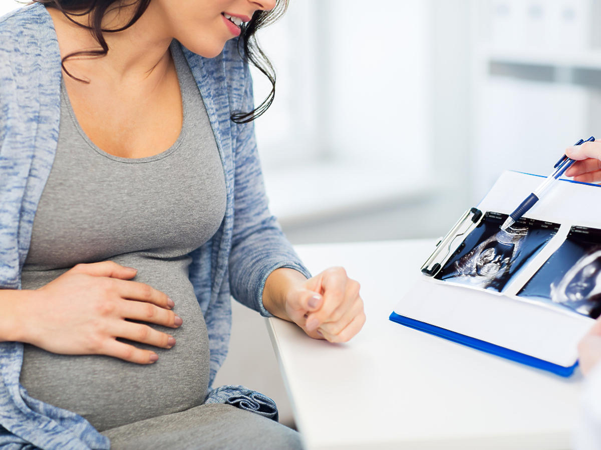 kobieta w ciąży oglądająca wynik badania w gabinecie lekarskim