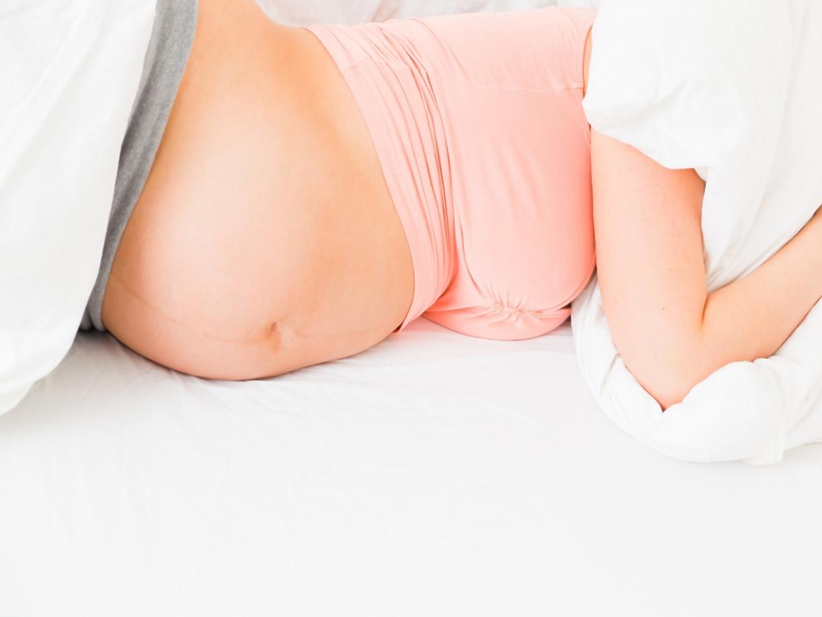 kobieta w ciąży przykrywa głowę poduszką