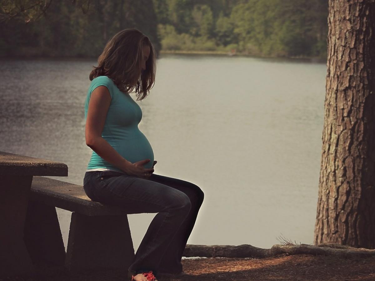 Kobieta w ciąży siedząca na brzegu jeziora