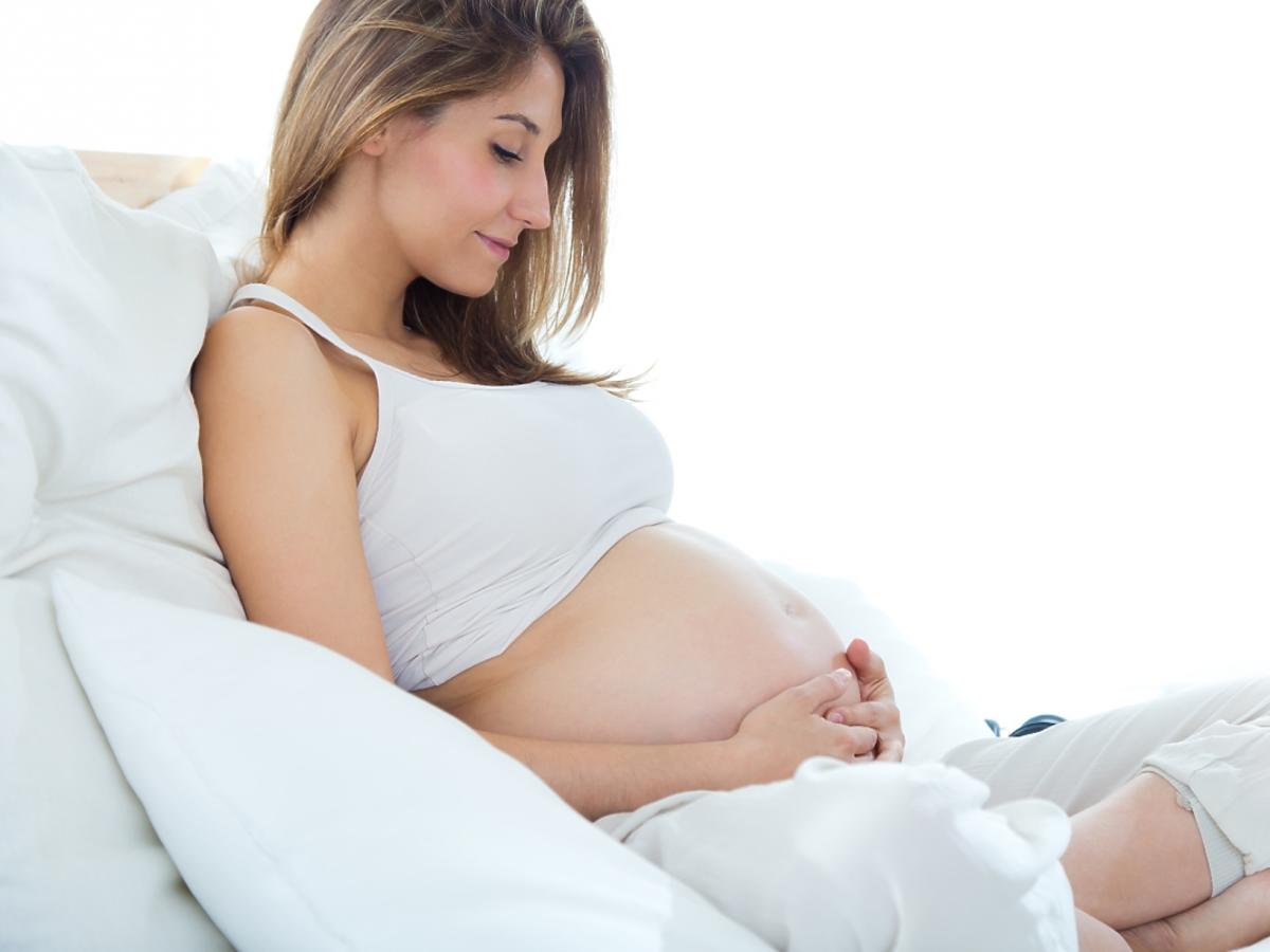 Kobieta w ciąży siedzi na kanapie