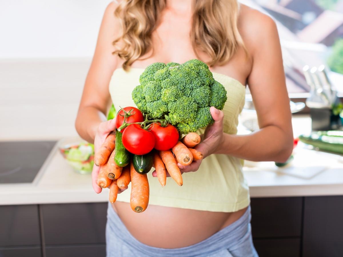 Kobieta w ciąży trzyma warzywa