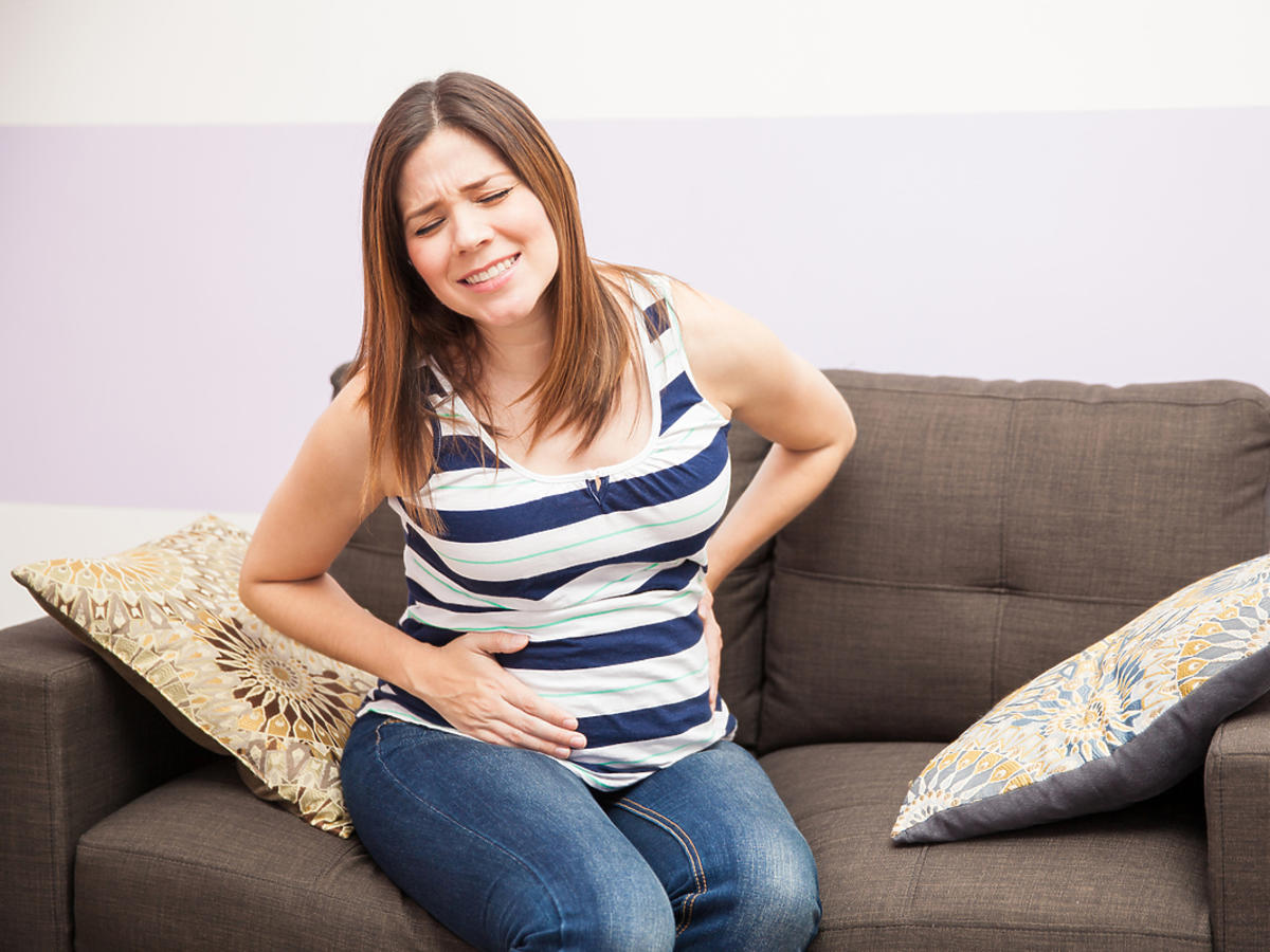 kobieta w zaawansowanej ciąży trzymająca się za brzuch