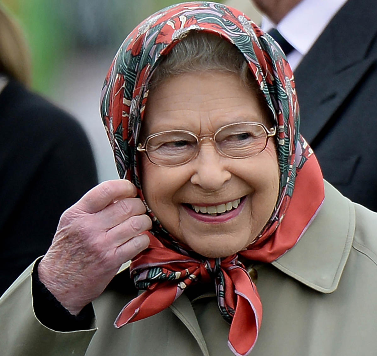 Królowa Elżbieta II, uśmiechnięta w chustce na głowie