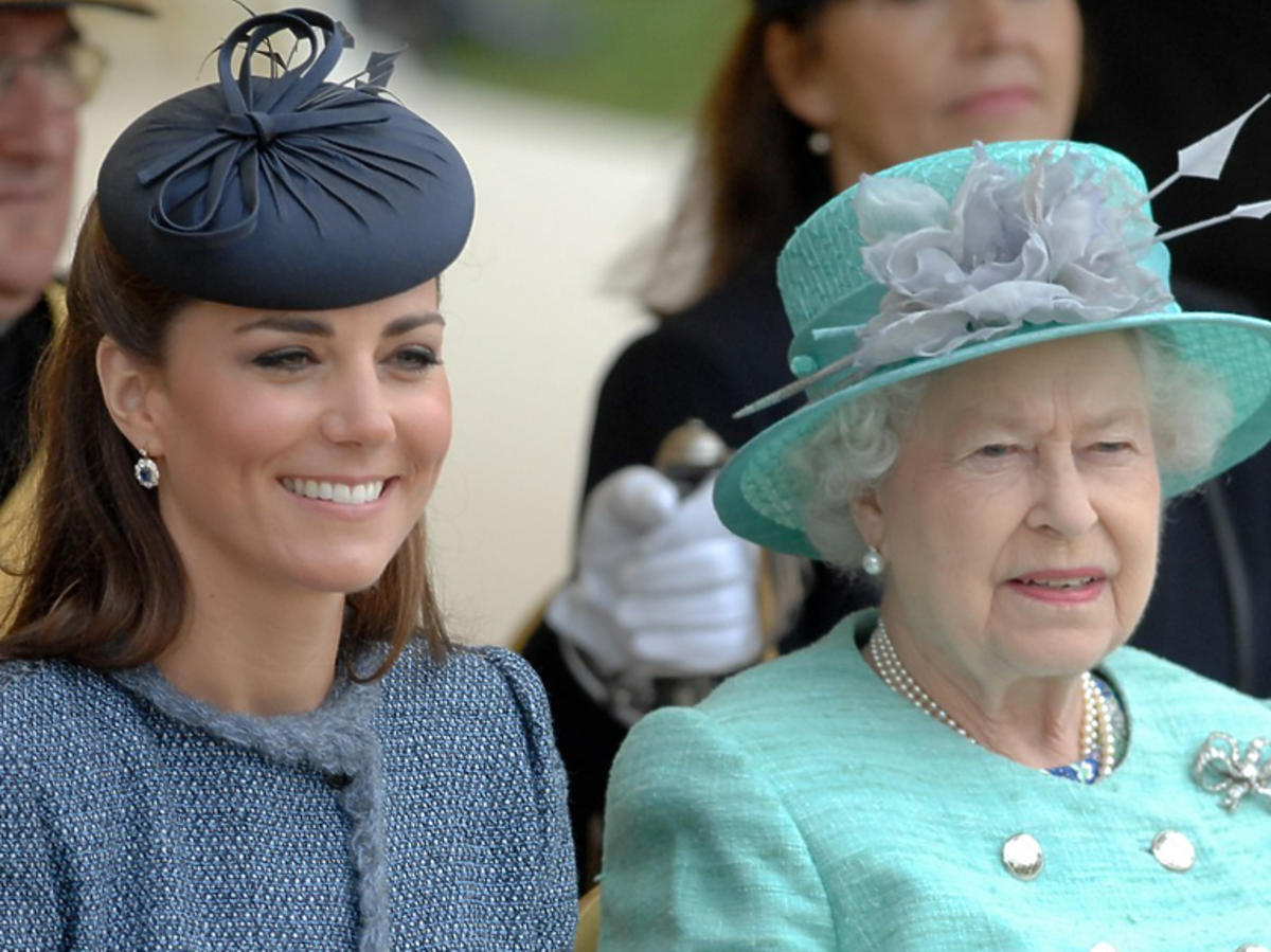 Księżna Kate w toczku i Elżbieta II w kapeluszu oglądają razem przedstawienie