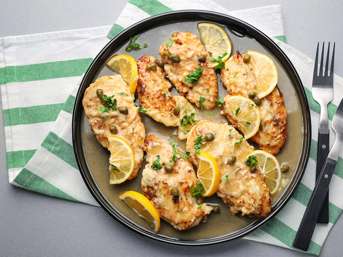 Kurczak piccata podany z na talerzu z cytyną.