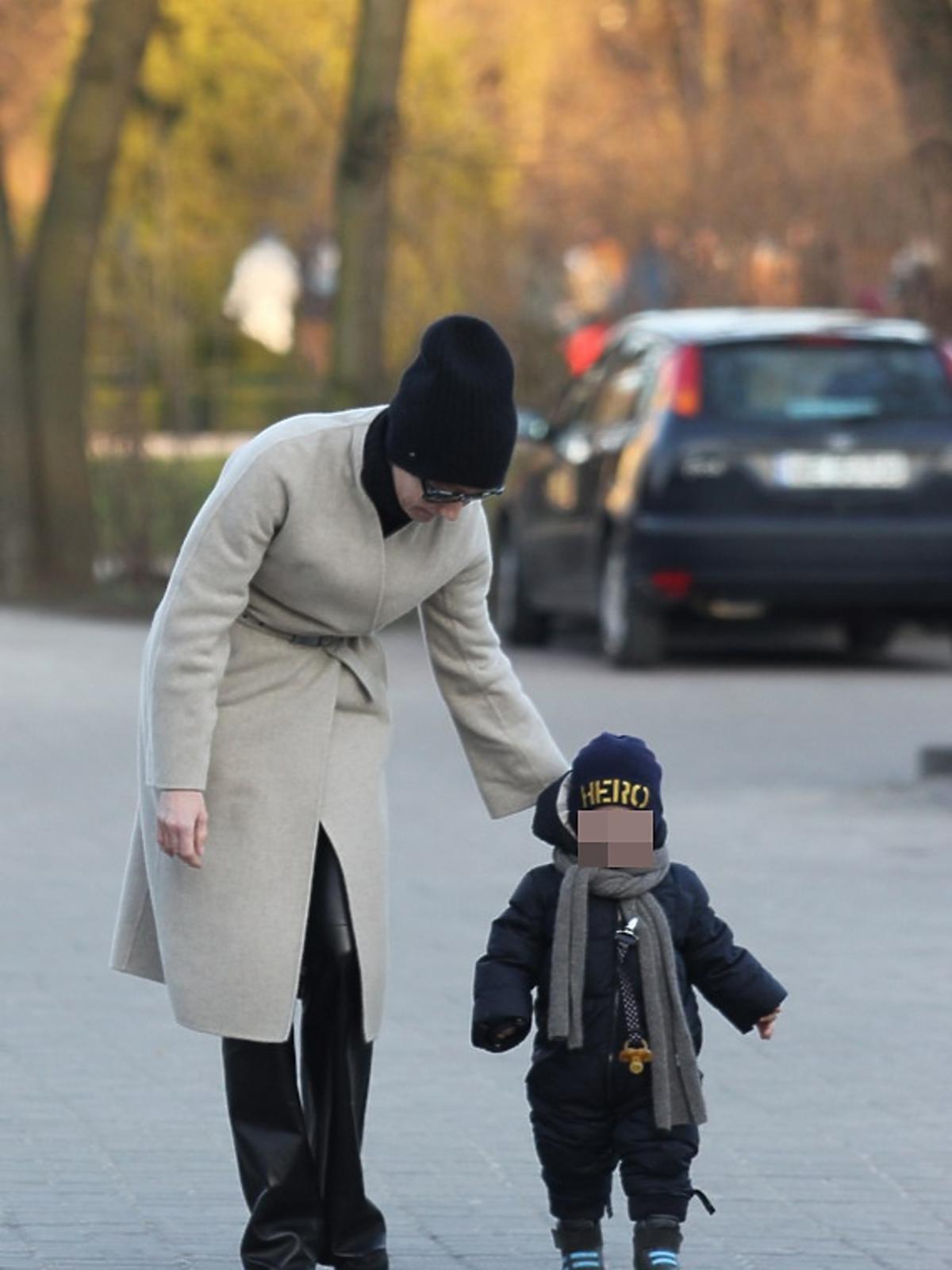 Małgorzata Kożuchowska w czarnych skórzanych spodniach z synem Jankiem w niebieskim kombinezonie idą ulicą