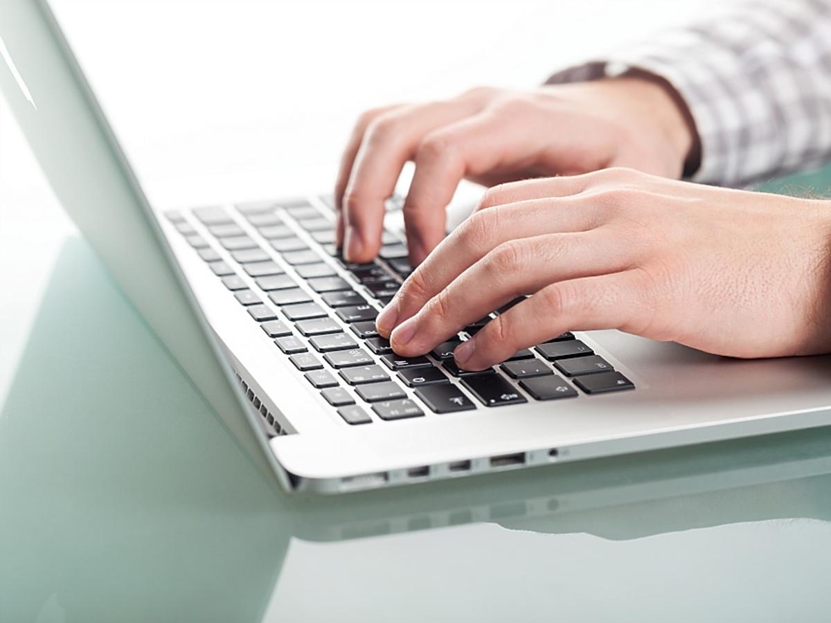 Mężczyzna pisze coś na laptopie