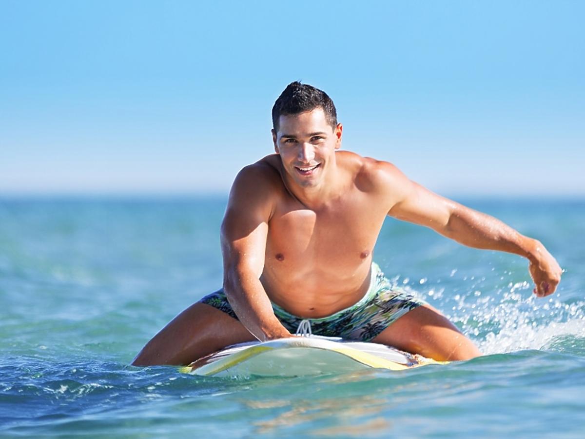 Mężczyzna płynie na desce surfingowej.