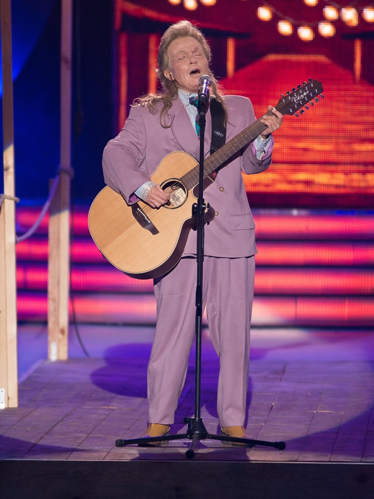Mężczyzna w fioletowym garniturze z gitarą