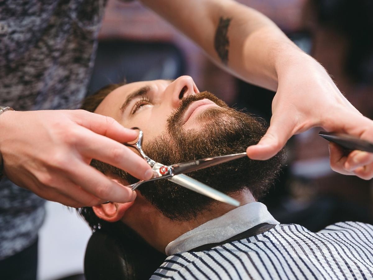 Mężczyzna znajduje się w salonie fryzjerskim na podcinaniu brody.