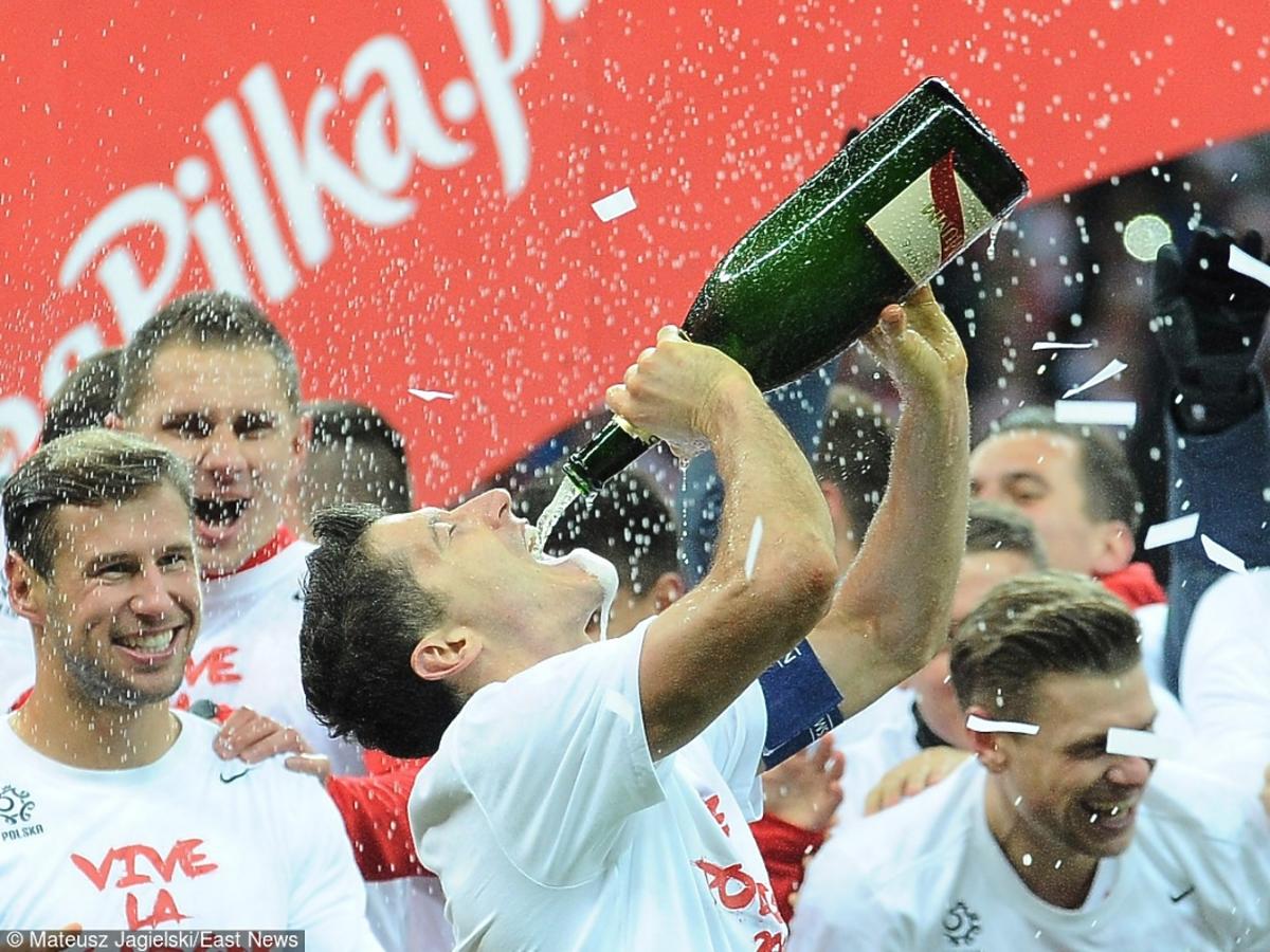 Robert Lewandowski pije szampana po zakończonym zwycięstwem meczu piłki nożnej przeciwko Irlandii