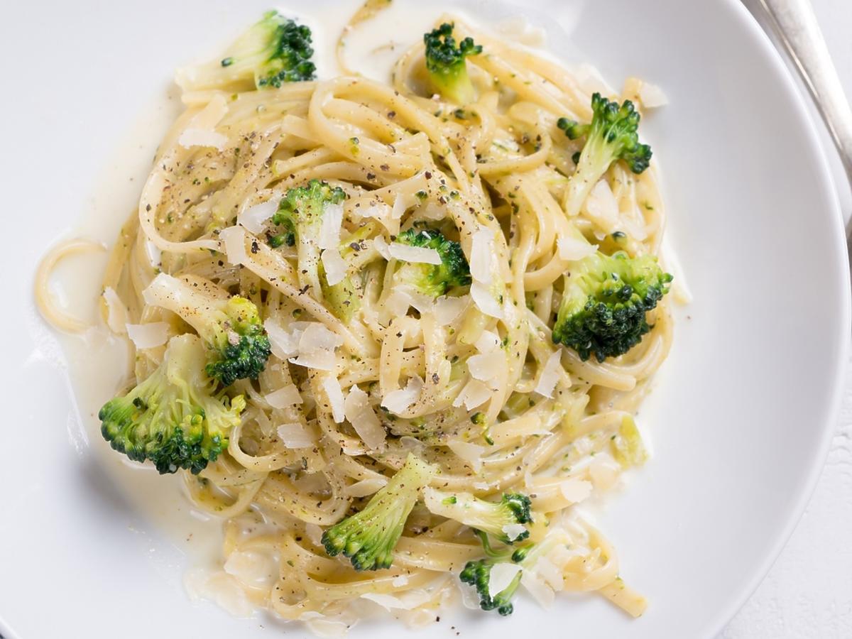 Spaghetti z brokułami i sosem śmietanowym na białym talerzu